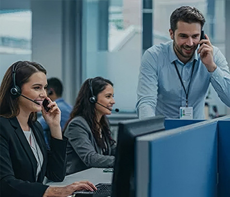 Customer support professionals using headsets and computer workstations in a modern contact center environment.