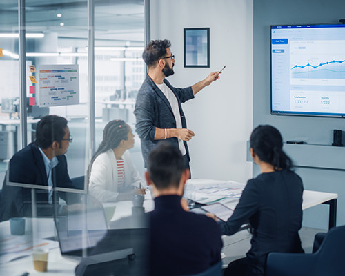 man looking at a screen explaining to colleagues