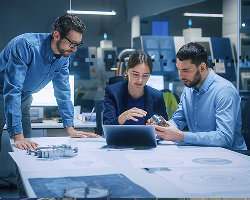 Three people in a tech room looking at a laptop