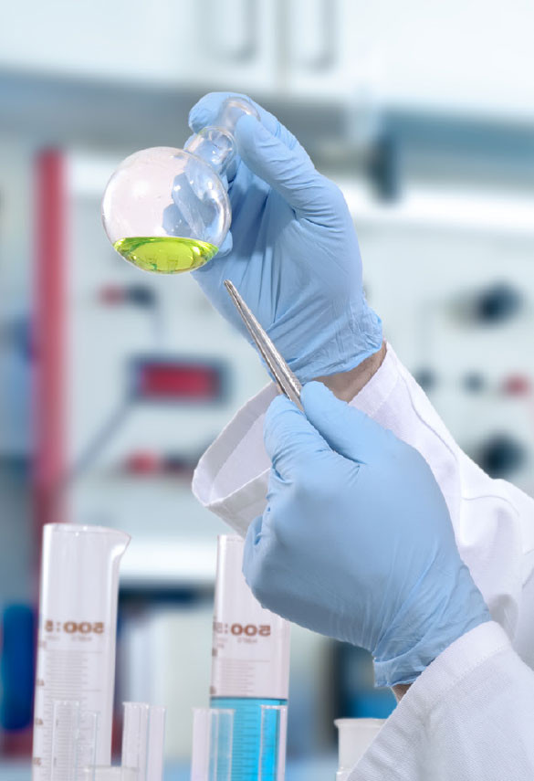 A set of hands in gloves holding glass tube with green fluid