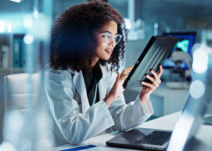 A lab technician looking into a tablet