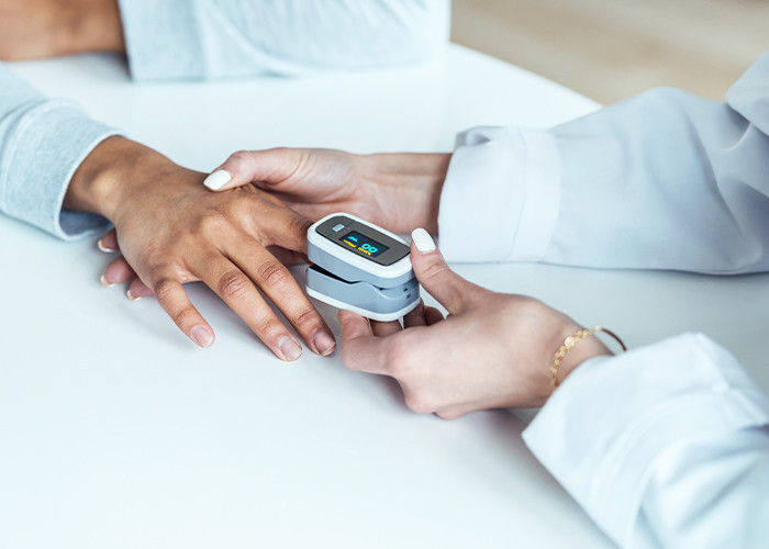 A doctor reading the BP of a patient by putting a device on a finger