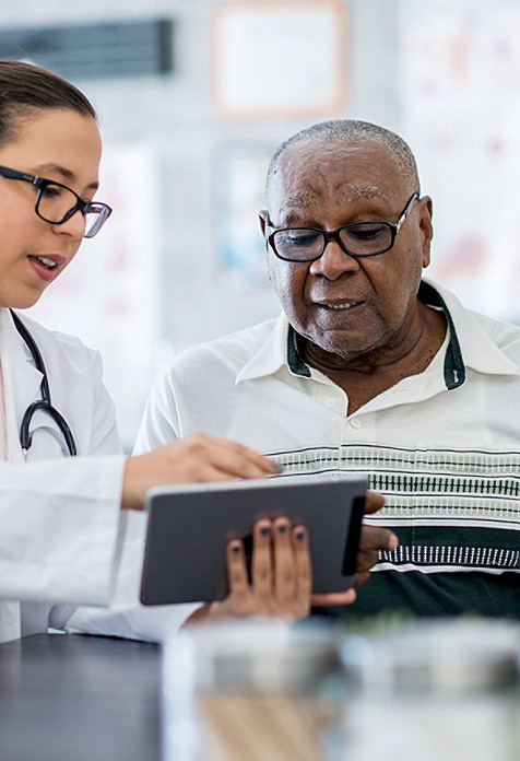 A doctor explaining a digital medical report to an elderly man.