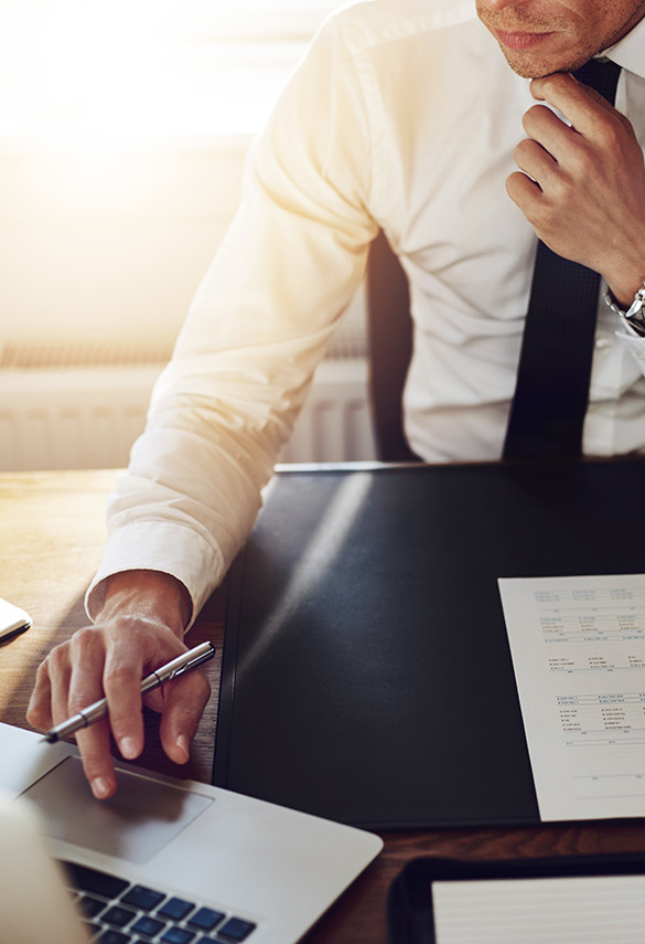 Man in suit holding a pen touching laptop