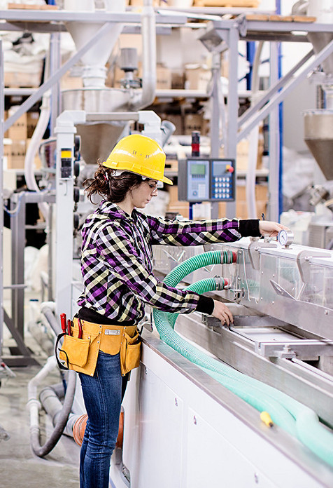 Femme verifiant une machine de fabrication