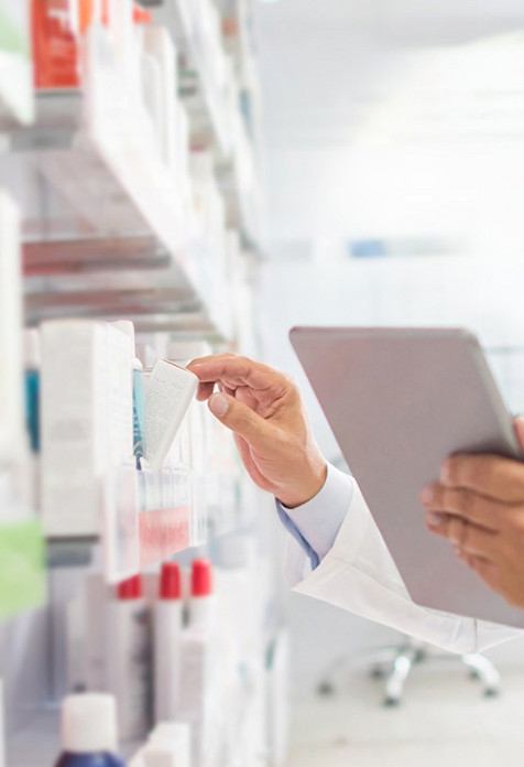 profesional sanitario revisando su tableta y eligiendo medicamentos del estante