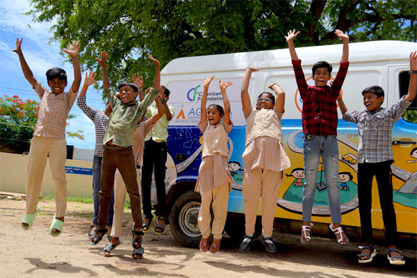 Children jumping infront of Mobile Science Lab Vehicle