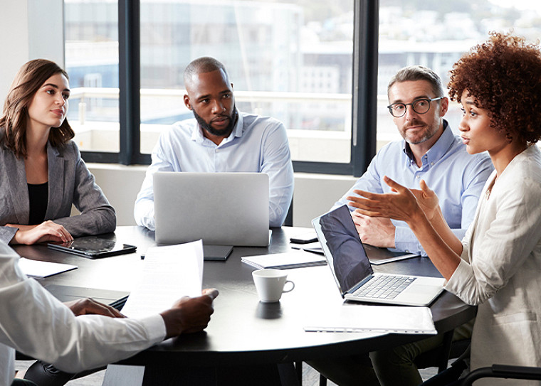 A group meeting in an office at a table with laptops open