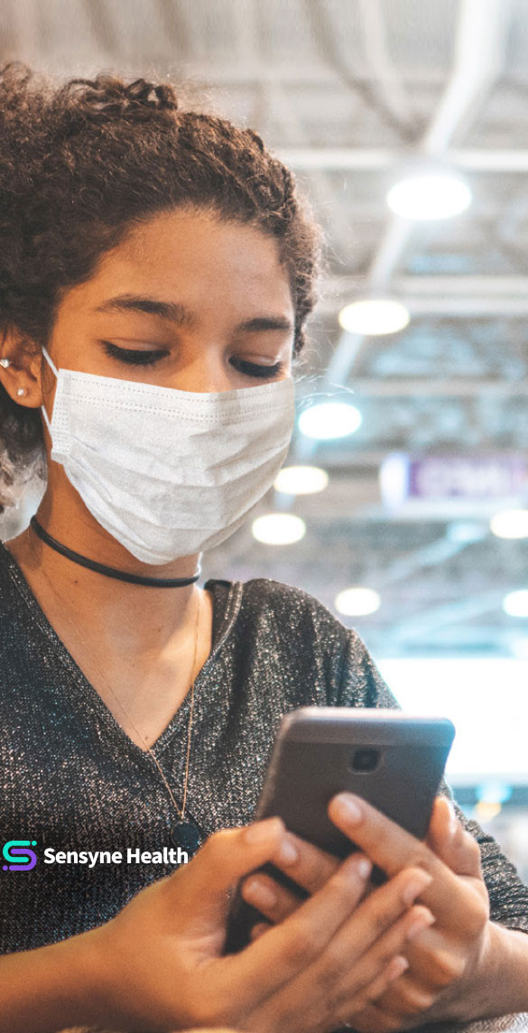 Frau mit Gesichtsmaske, die auf das Handy schaut