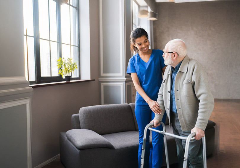 A woman care worker assisting an old patient to walk