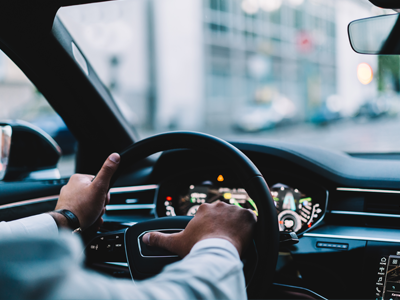 View of a man hands on the steering wheel of a car.
