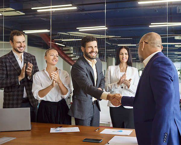 Office workers congratulating a colleague in a meeting room 