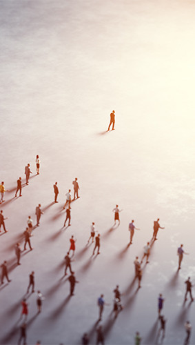 Vista aérea de una persona caminando delante de un gran grupo de personas, hacia una luz brillante.