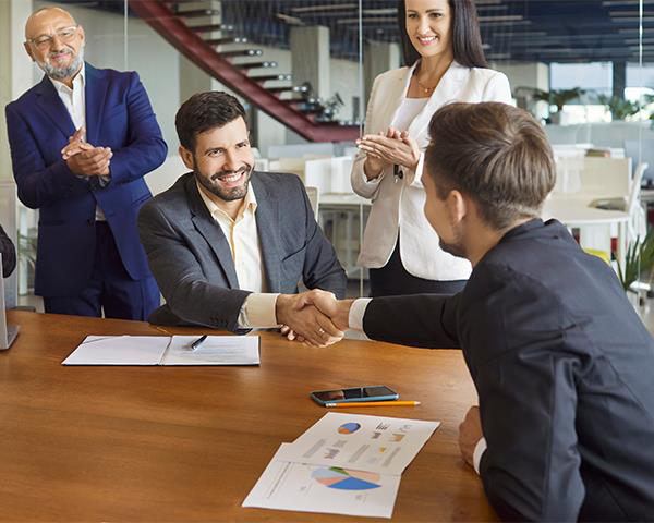 Office workers congratulating a colleague in a meeting room 