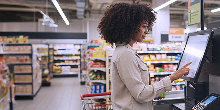 A female customer at a self service POS in a grocery store.
