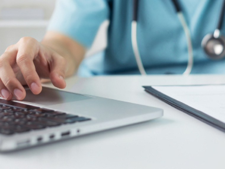 Closeup view of a medical professional's hand on the laptop