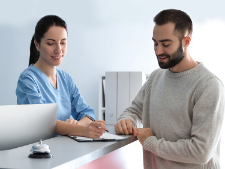 A woman signing on a paper while a man looking at it