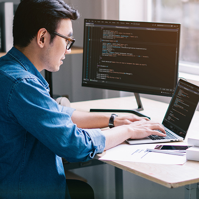 A young man working on a laptop at his desk