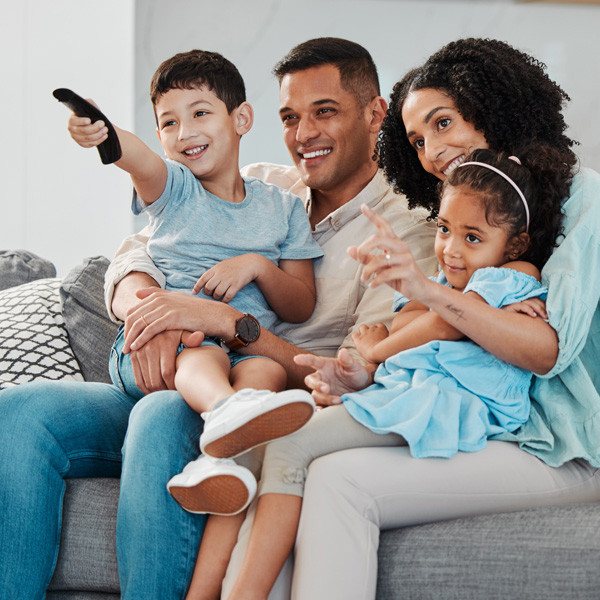 A family of father, mother and two kids happily watching tv