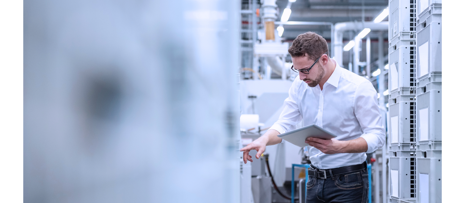 A man in a white shirt, holding a tablet, while examining something