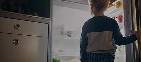 Kind schaut in einen Kühlschrank