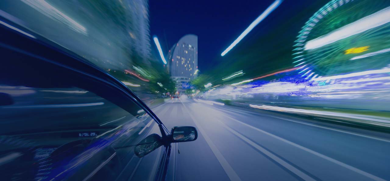 A fast-moving car on the road at night.
