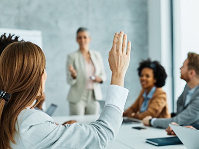A women raise his hand in a business meeting