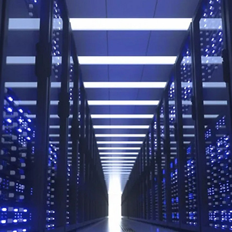 A blue-themed server room with servers stacked on both sides and light at the end of the tunner-like aisle