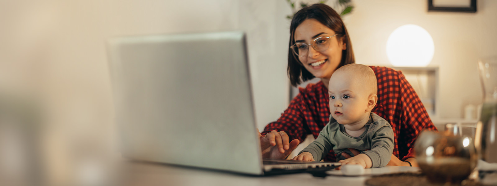 a smiling woman and a baby looking at a laptop screen