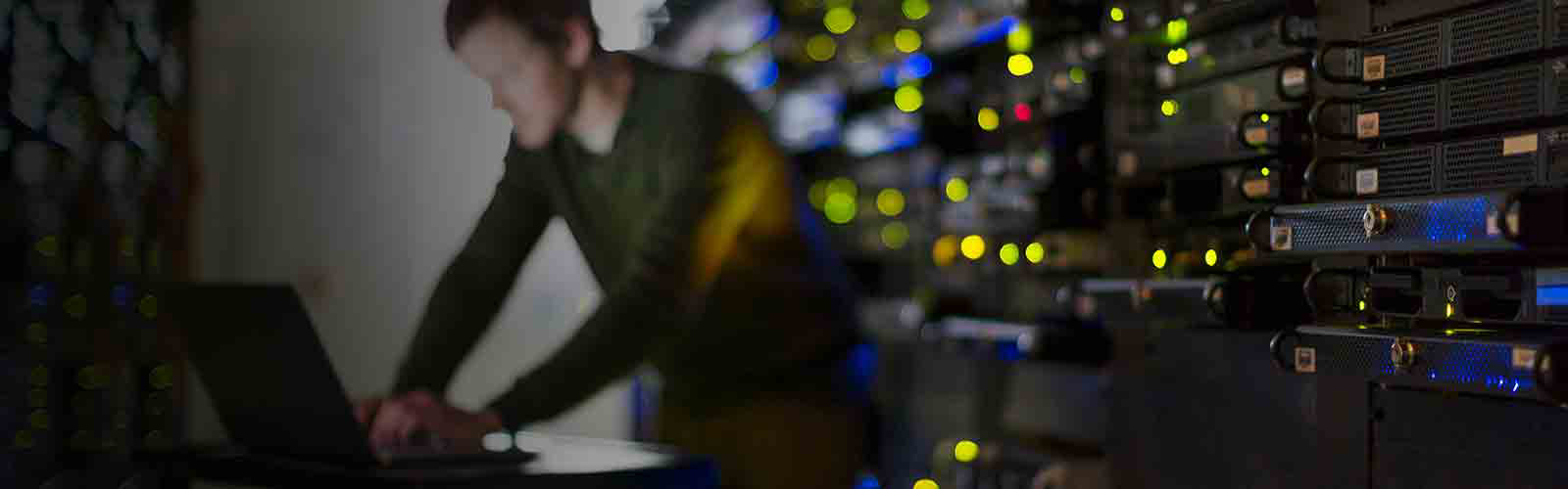 Uskarpt bilde av en mann som jobber på en bærbar datamaskin i et serverrom