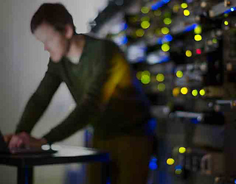 Blurred image of man working on a laptop in a server room