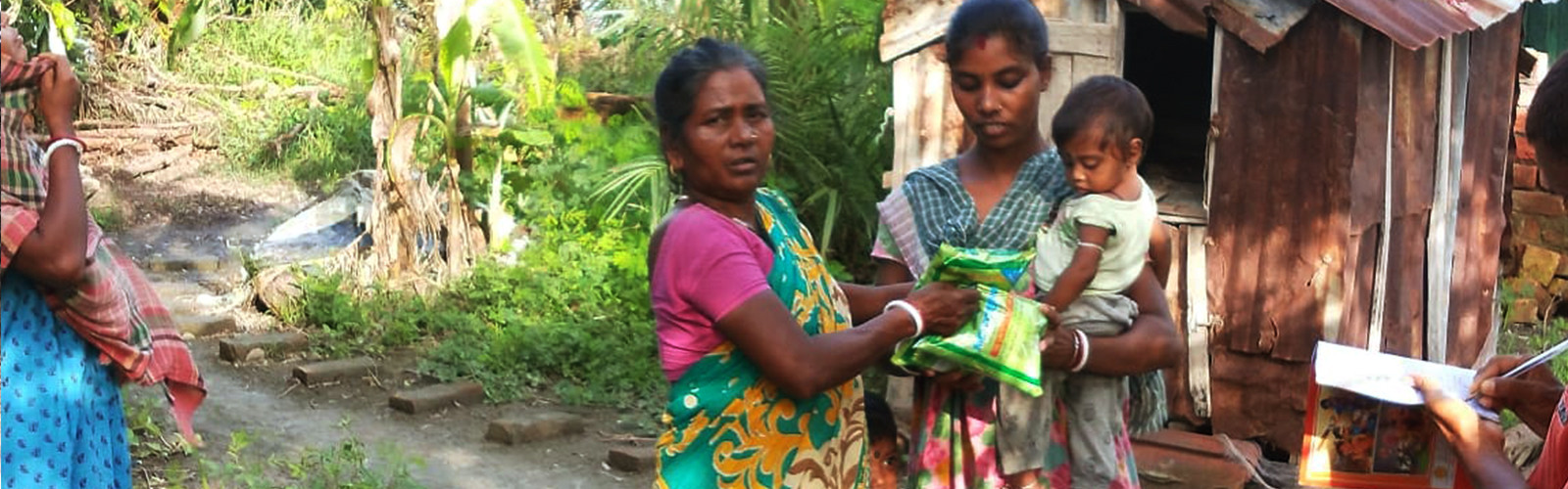 A lady is giving groceries to a women having child