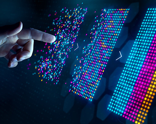 A finger pointing at a digital screen with panels of colorful dots