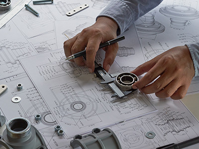 Primer plano del ingeniero trabajando en planos, usando herramientas de calibre para medir