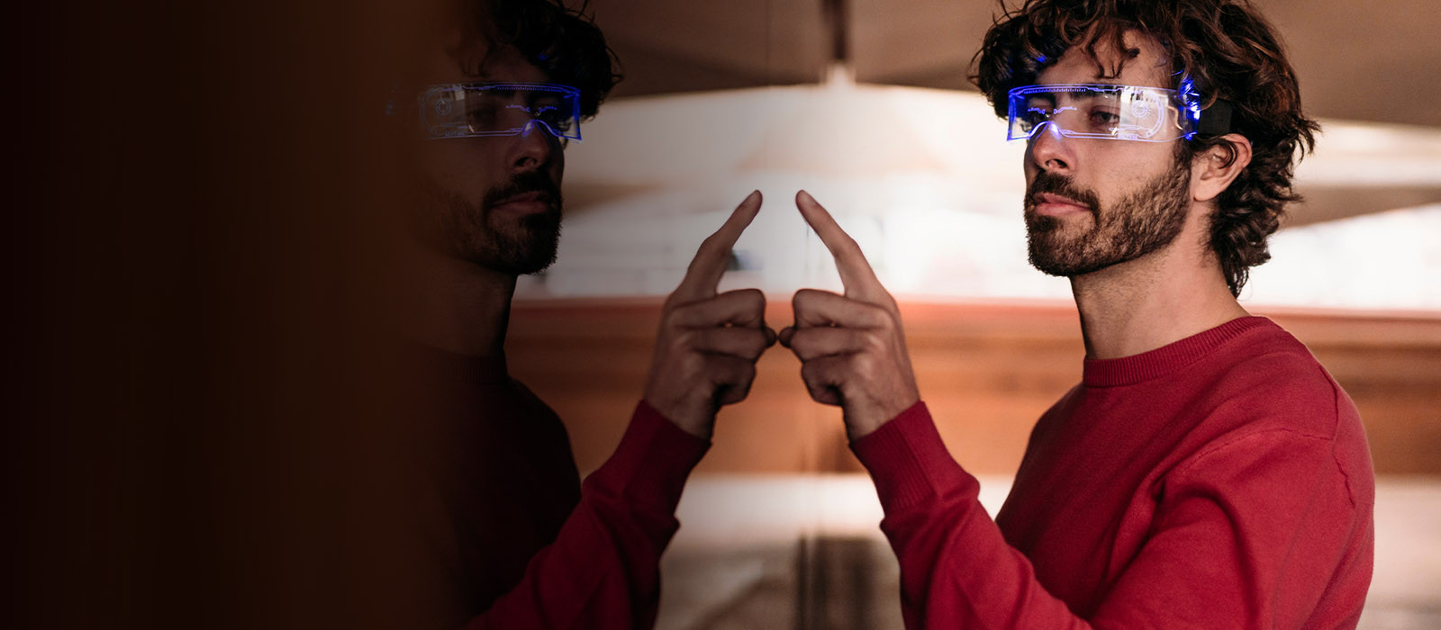 man wearing digital glasses pointing at a mirror