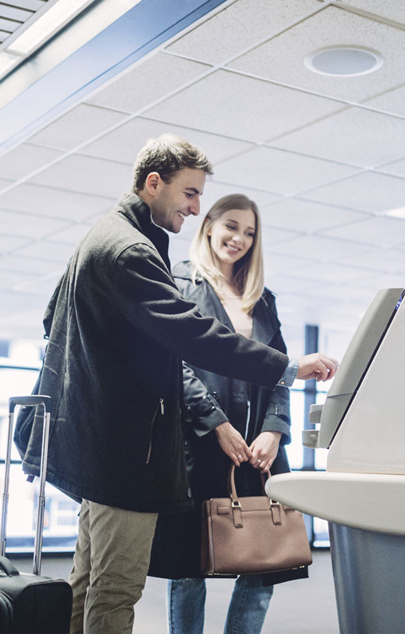 Man standing next to woman in front of a kiosk machine