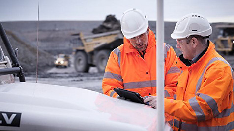 to fabrikkarbeidere ser på en dataskjerm