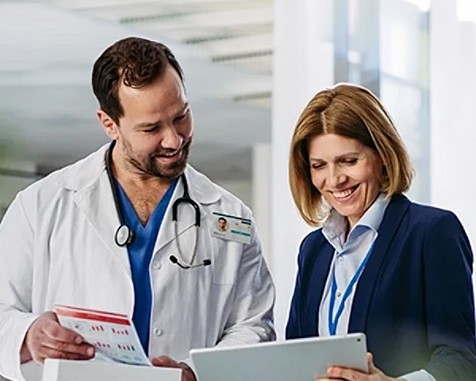 Doctor reviewing patient reports with colleague on tablet in a hospital setting