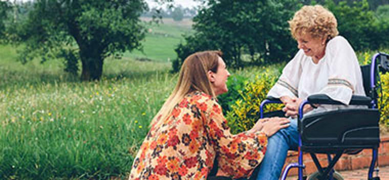 Women talking to elderly physically challenged person