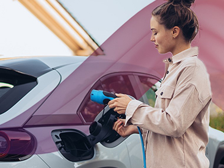 A woman connects her electric car to a charging station, preparing to recharge its battery.