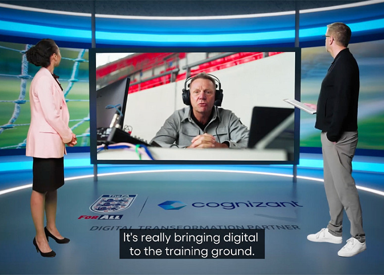 Two TV hosts watching an expert speak on a screen