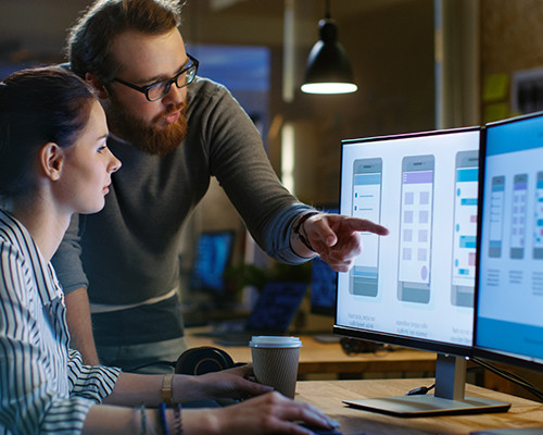 a man explaining to a woman looking at a monitor