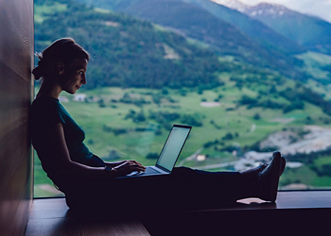 Eine Frau sitzt auf dem Boden und benutzt ihren Laptop