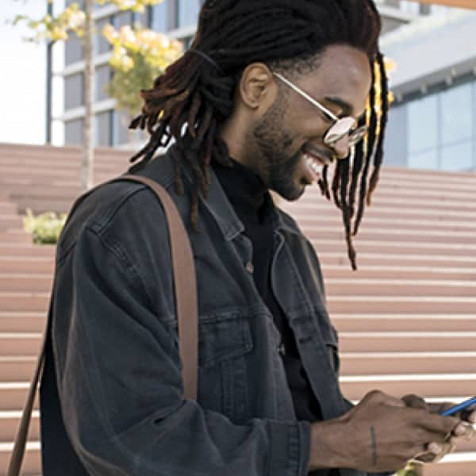 ein Mann, der in sein Mobiltelefon lächelt