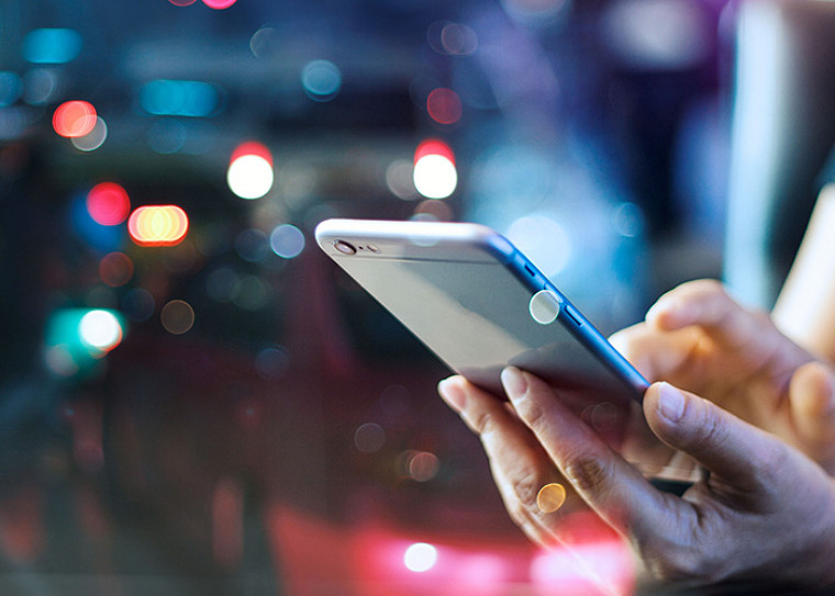 A person's hand holding a mobile phone and interacting with it