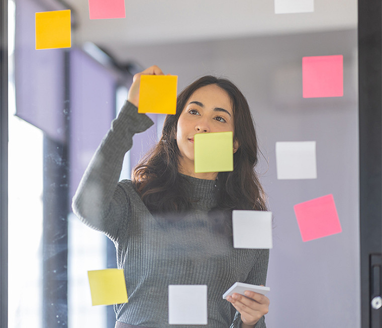 A woman sticking notes on a glass wall