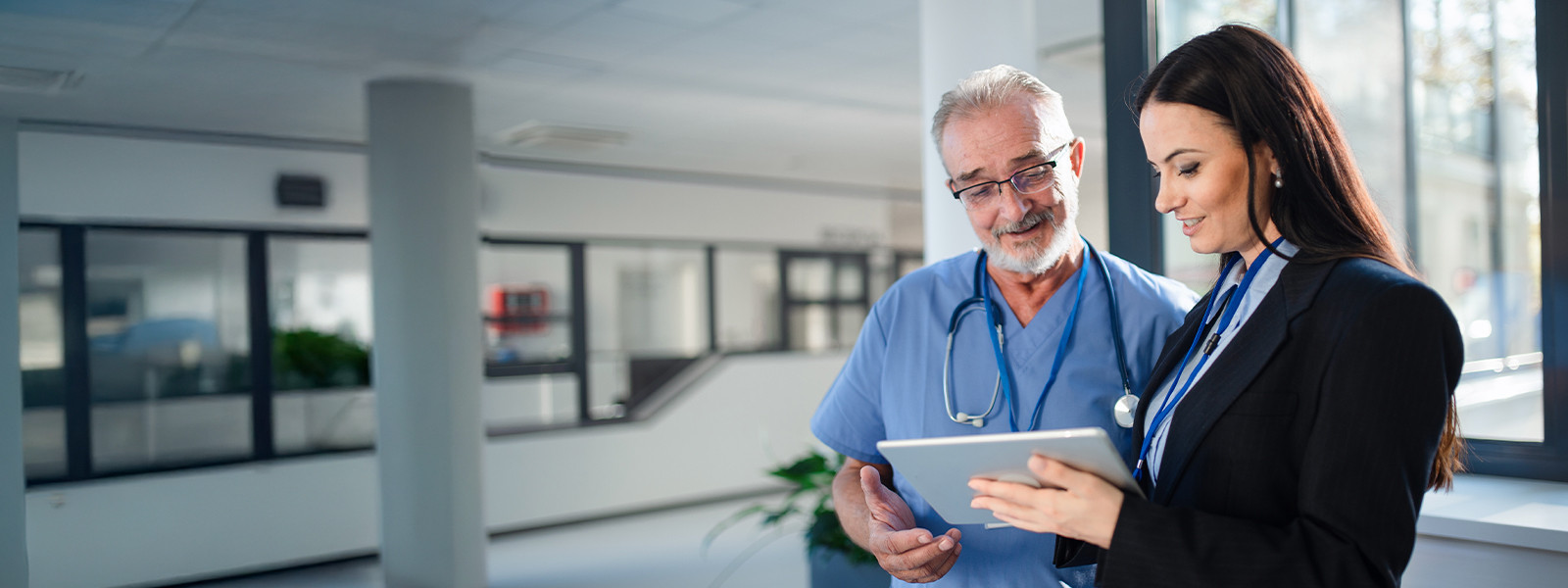 A woman and a man in a hospital examining a tablet together, engaged in discussion about its content.