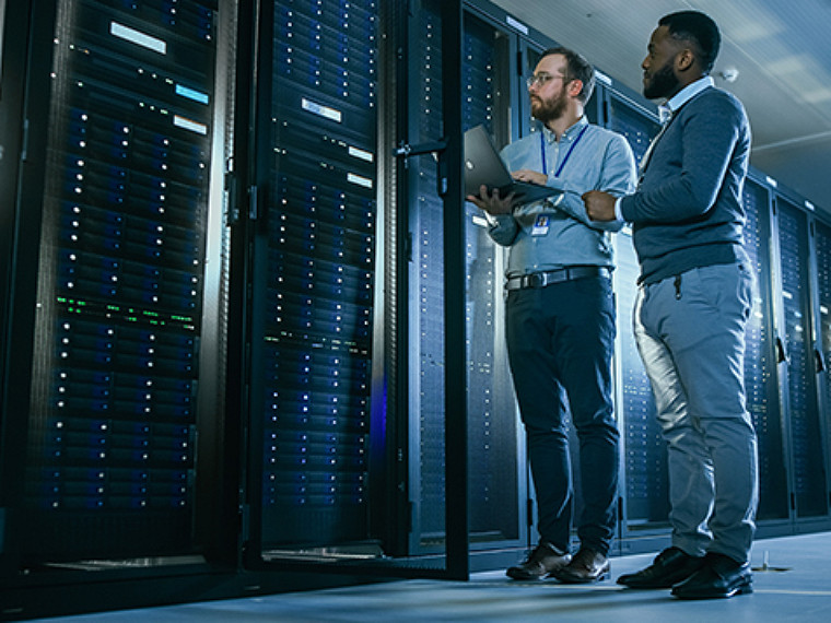 Two people standing and looking at servers