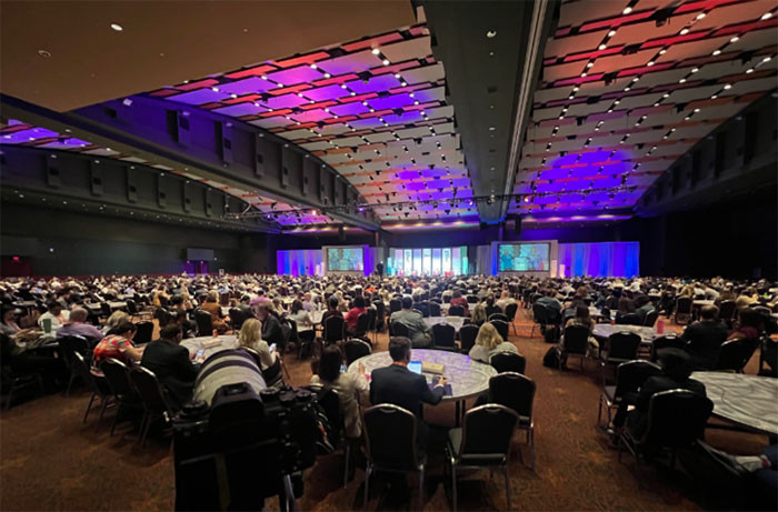 A large group of people seated at tables in a conference hall