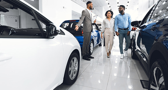 A car  saleman in conversation with customers in a car showroom